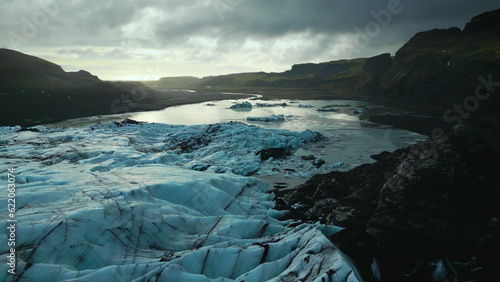 Drone shot of ice mass on frozen water, huge icy blocks floating on lake in iceland. Beautiful blue arctic landscapes and scenery with vatnajokull glacier cap, panoramic view. Slow motion.