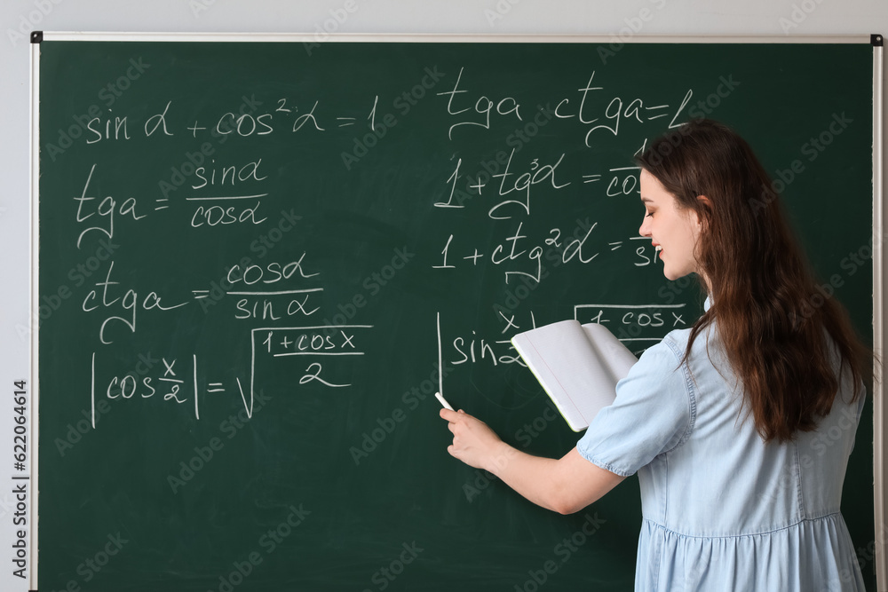 Female Math teacher writing on chalkboard in classroom