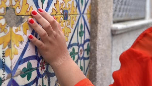girl tourist walks along old Porto street touching red nailed hand wall with azulejo tiles, close view photo