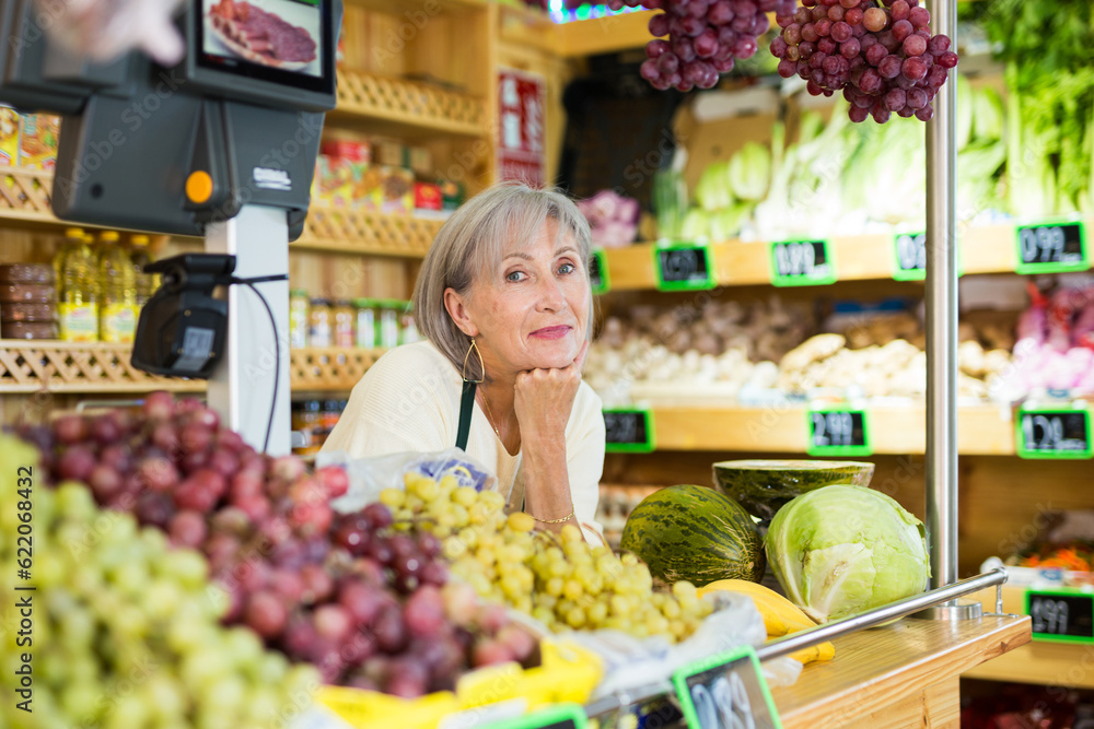 Senior caucasian woman seller standing at counter in greengrocer.