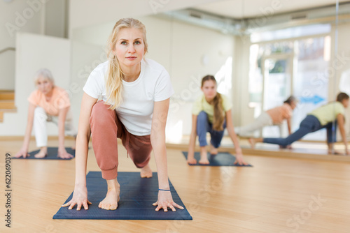 Active adult woman exercising stretching workout and incline during yoga class in fitness studio