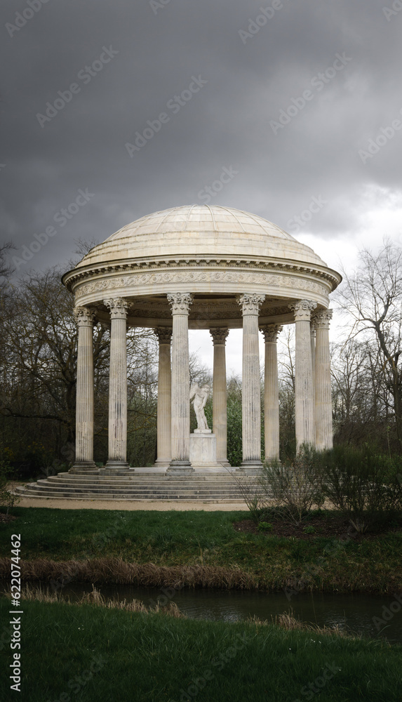 The Temple de l'Amour or the temple of love from the beautiful garden of the royal estate Petit Trianon. Marble columns, carved cupola roof shape and a cupid statue in the center of the monument.