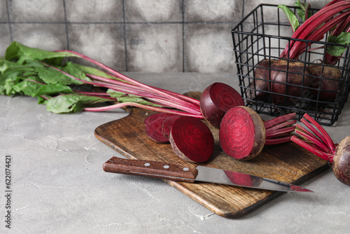 Cutting board with fresh cut beetroots and knife on grey table