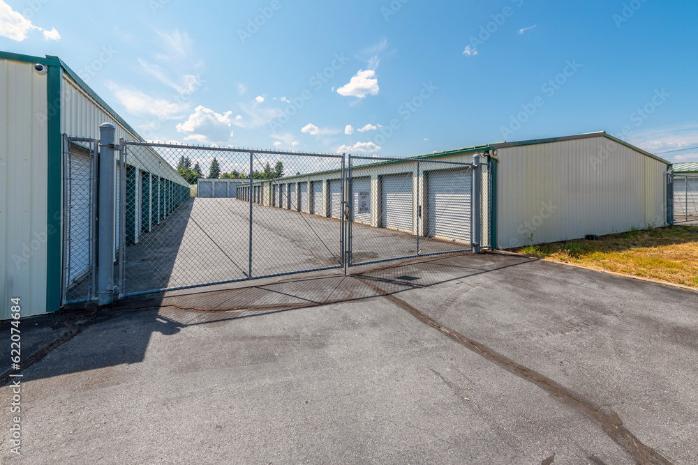Obraz premium Garage storage units for rent behind a chain link fenced gate at a storage complex business.
