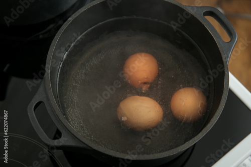 Three brown eggs boiling in...