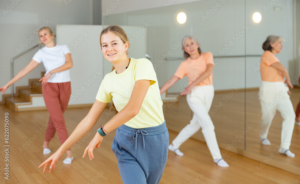Young girl performing aerobic dance during group training with her mother and grandmother.