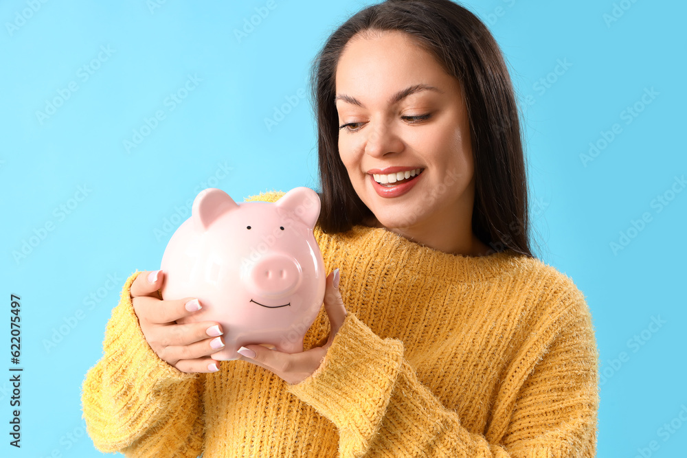 Young woman with piggy bank on blue background, closeup Young woman with piggy bank on blue background, closeup