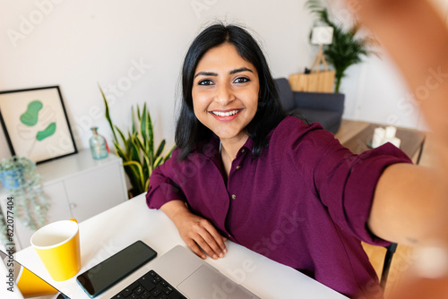 Photography Smiling young adult indian student woman taking selfie while working on laptop at home