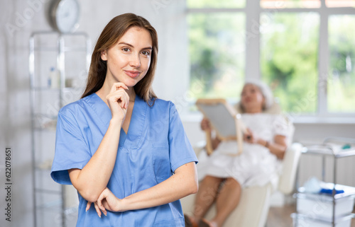 Portrait of serious female surgeon standing with patient looking at mirror in background before examination.