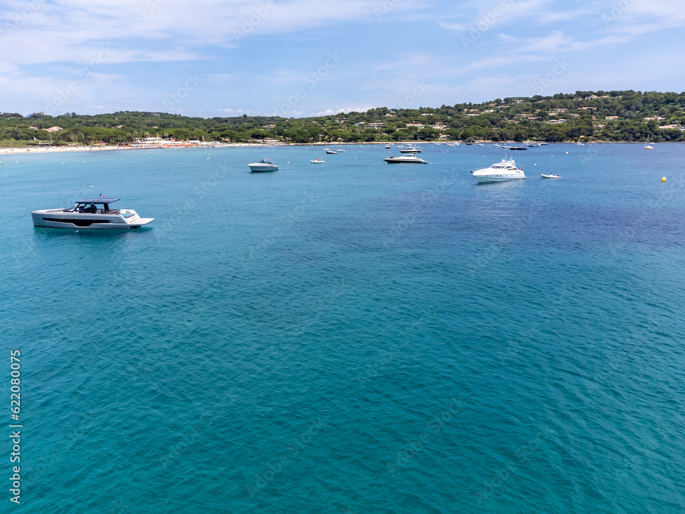 Obraz premium Aerial view on boats, crystal clear blue water of legendary Pampelonne beach near Saint-Tropez, summer vacation on white sandy beach of French Riviera, France