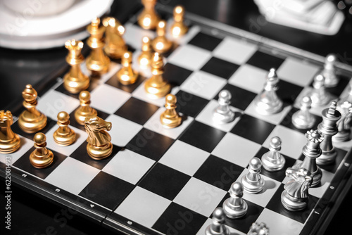 Golden and silver chess pieces on game board, closeup