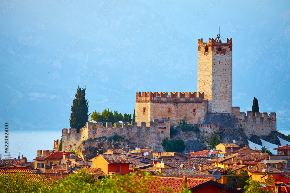 Ancient tower and fortress in old town Malcesine at Garda lake, Veneto region, Italy. Summer landscape with house roofs