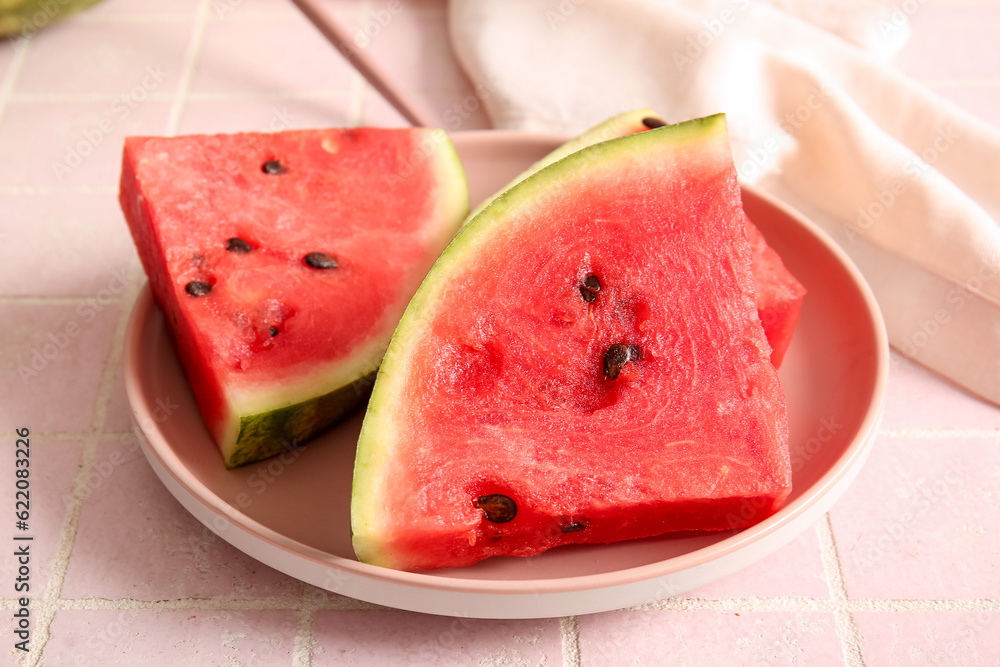 Plate with pieces of fresh watermelon on pink tile table Plate with pieces of fresh watermelon on pink tile table