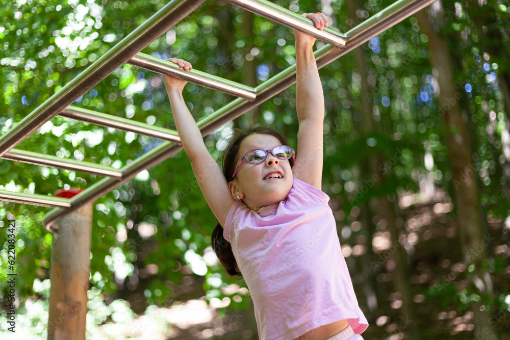 Little girl doing pull-ups on a horizontal bar in the park Little girl doing pull-ups on a horizontal bar in the park