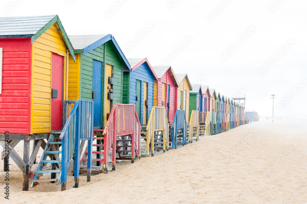 Naklejka premium Multi-colored beach huts disappearing in the mist at Muizenberg in Cape Town, Western Cape Province of South Africa