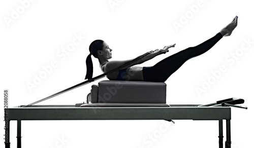 one caucasian woman exercising pilates reformer exercises fitness in silhouette isolated on white backgound photo