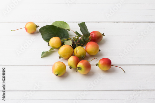 Small ripe ranetki apples on a white wooden background, top view