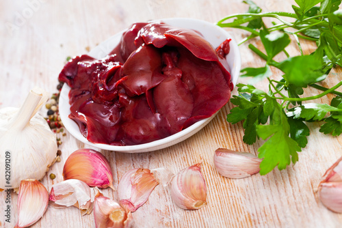 Image of raw rabbit liver with garlic and greens during cooking
