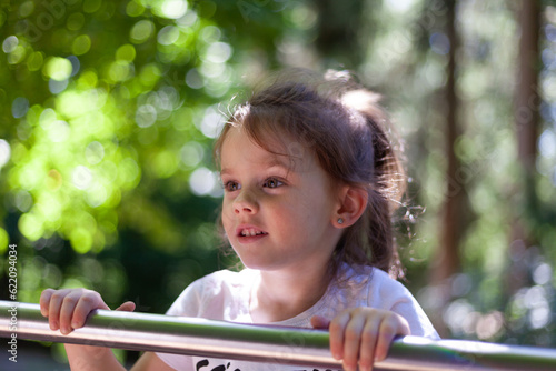 Portrait of a cute little girl playing on the playground in summer