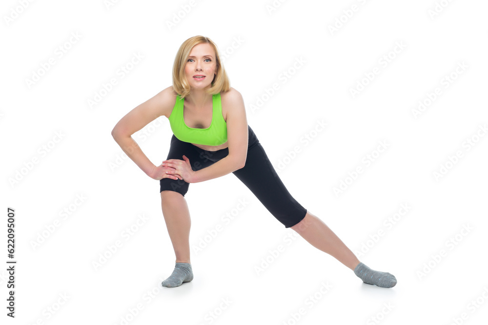 Beautiful middle aged blond fit woman in green bra top and black pants doing sport exercise. Isolated over white background. Copy space. Beautiful middle aged blond fit woman in green bra top and black pants doing sport exercise. Isolated over white background. Copy space.