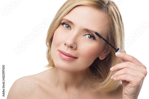 Beautiful middle aged woman with smooth skin and short blond hair applying fix gel to eyebrows. Beauty shot. Isolated over white background. Copy space.