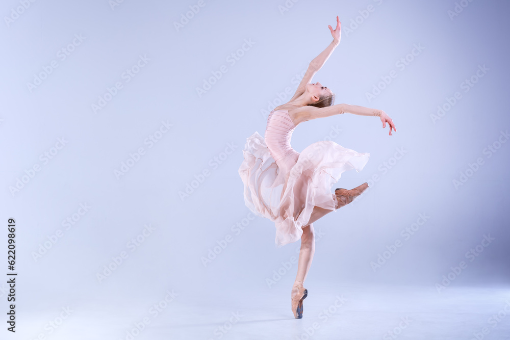 Young ballerina is dancing in a white studio full of light