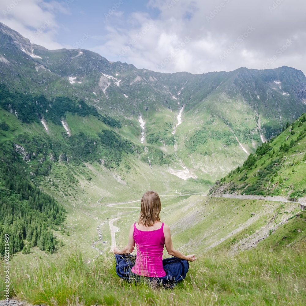 Young woman meditate on the top of mountain