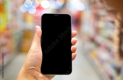 Hand holding black mockup smartphone and blurred background whit bokeh, telephone on the hand for presentation product and activities, life slyle concept