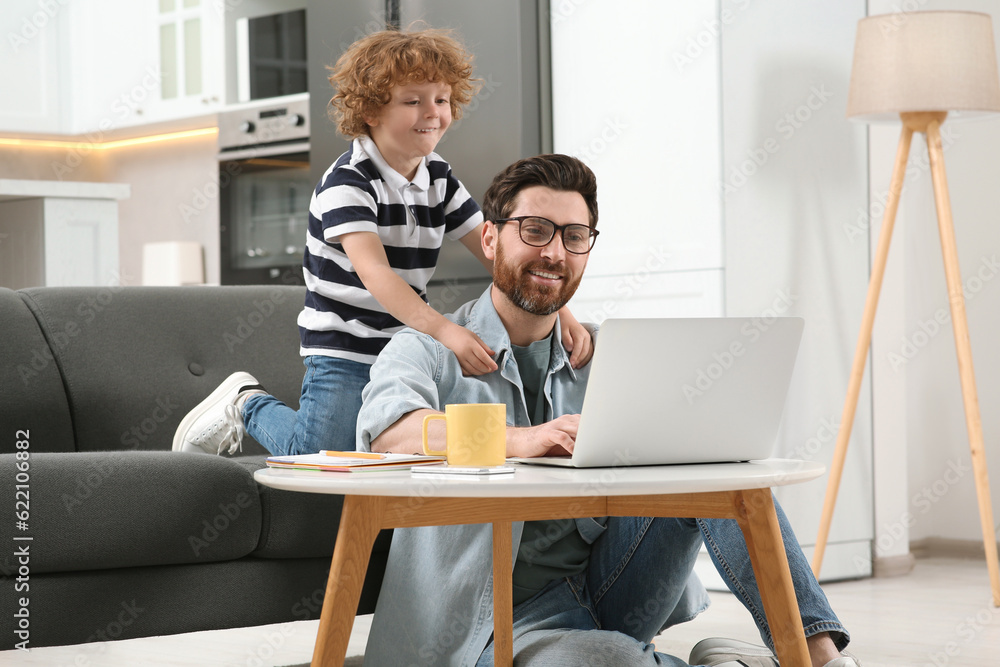 Man with laptop working remotely at home. Father and son at desk Man with laptop working remotely at home. Father and son at desk