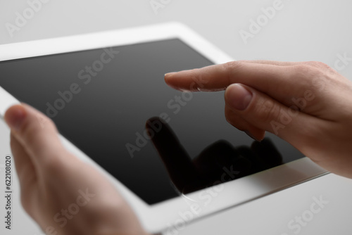 Closeup view of woman using modern tablet on light grey background