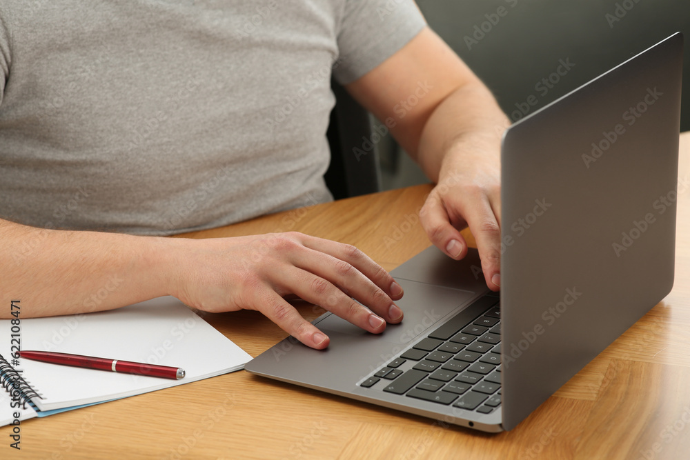 Man working with laptop at wooden table, closeup Man working with laptop at wooden table, closeup