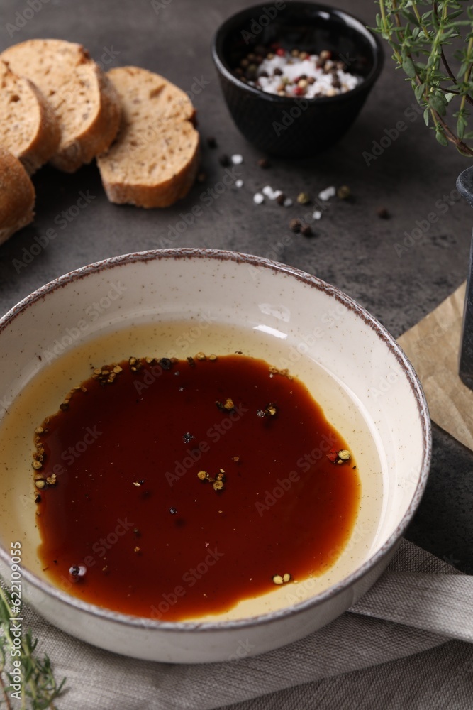 Bowl of balsamic vinegar with oil, spices and bread on dark grey table Bowl of balsamic vinegar with oil, spices and bread on dark grey table