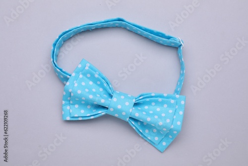 Stylish light blue bow tie with polka dot pattern on grey background, top view