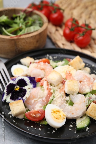 Delicious Caesar salad with shrimps served on grey table, closeup