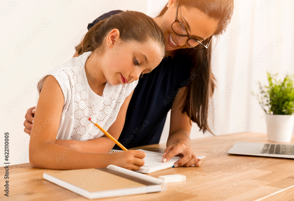 Mother and daugther at home doing homework together Mother and daugther at home doing homework together