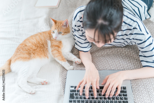 家で猫と一緒にパソコンでテレワーク・リモートワークする女性（アニマルセラピー・在宅勤務・在宅ワーク）
