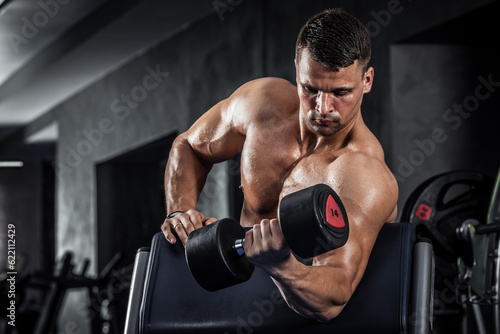 Brutal athletic man pumping up muscles with dumbbells © Designpics