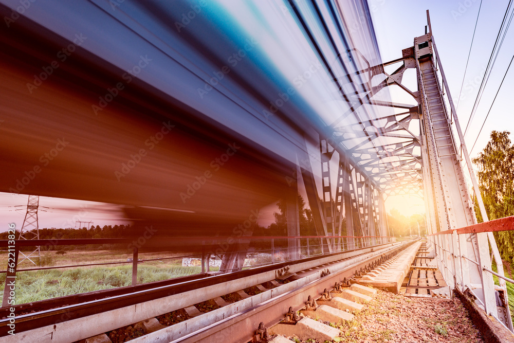 Fototapeta premium Highspeed train moves fast on the bridge at sunsset.