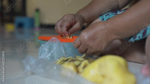 Close up of Asian woman's hand grating potatoes in the kitchen photo