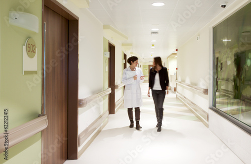 Doctor explaining something to a patient while walking through a hospital corridor.