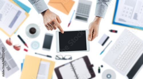 Businessman using a digital touch screen tablet, hands close up top view, desktop on background