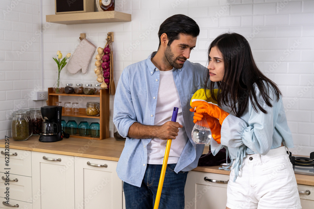 Young happy couple having fun while doing cleaning kitchen together Young happy couple having fun while doing cleaning kitchen together