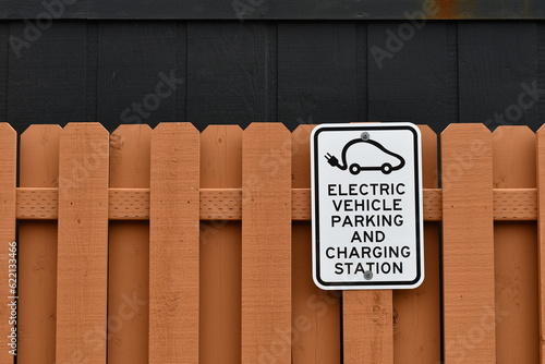 Electric vehicle parking and charging station sign on wooden fence. photo