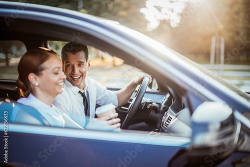 Fotografiet Young businessman and businesswoman driving a car and commuting to work