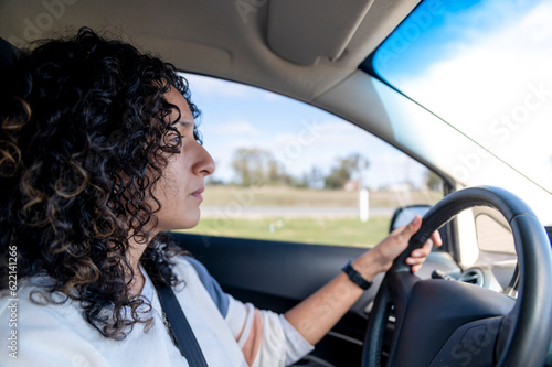 Young serious woman driving a car on the road.