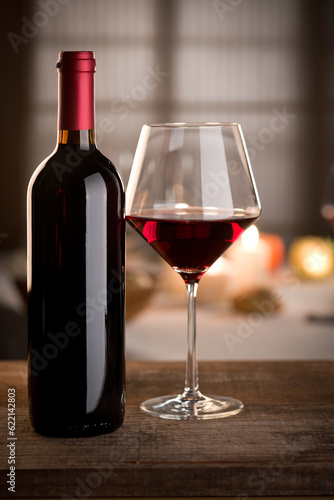 Red wine glass and bottle close up with restaurant on background.