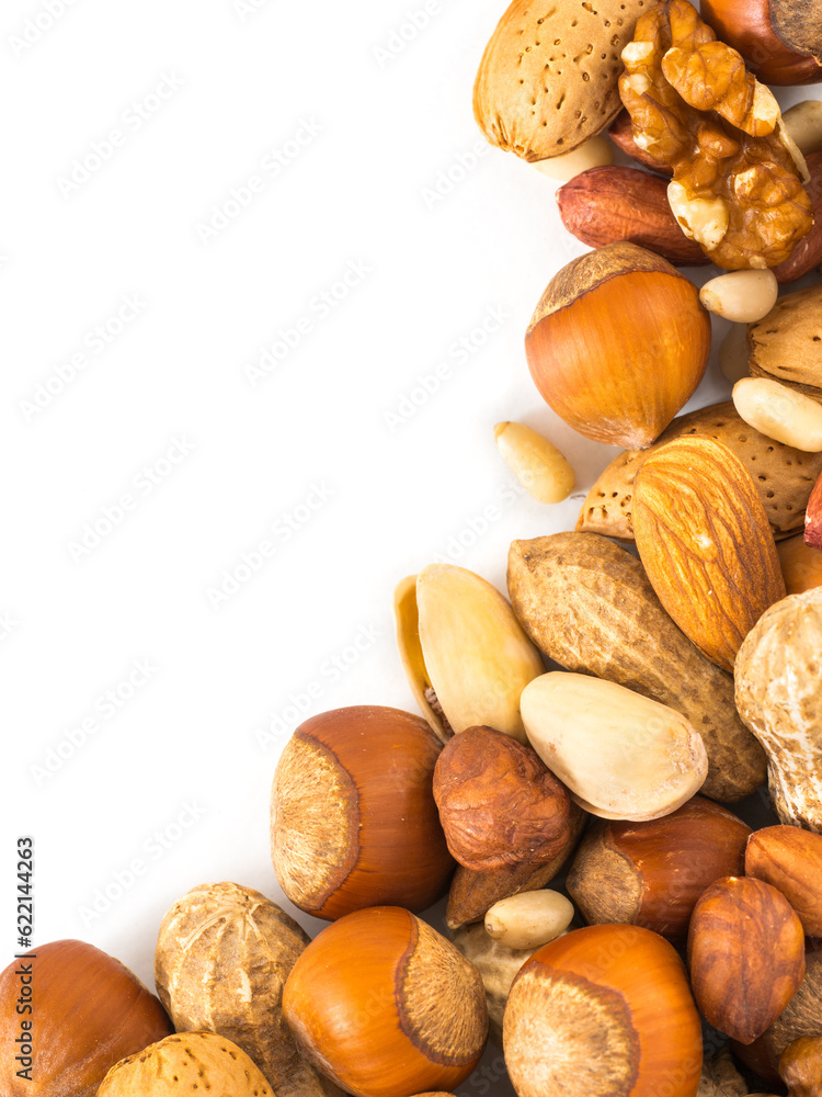 Background of mixed nuts - hazelnuts, almonds, walnuts, pistachios, peanuts, pine nuts peeled and not peeled - vertical with copy space. Isolated one edge. Top view or flat lay Background of mixed nuts - hazelnuts, almonds, walnuts, pistachios, peanuts, pine nuts peeled and not peeled - vertical with copy space. Isolated one edge. Top view or flat lay