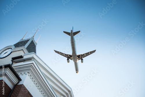 Plane flying by over a building with a clock