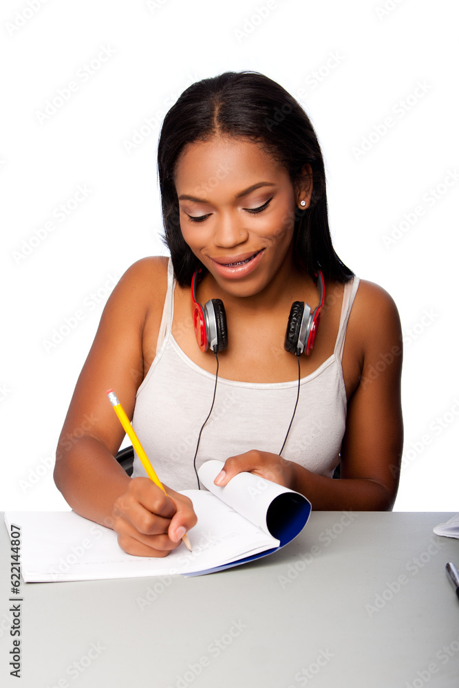 Cute beautiful happy smiling teenage student doing homework writing in notebook sitting at desk, on white. Cute beautiful happy smiling teenage student doing homework writing in notebook sitting at desk, on white.