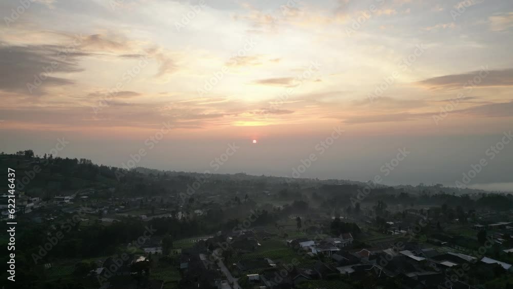 Aerial view of Beautiful sunrise at Mount Merbabu mountainside in the morning with vegetable garden and village settlements or housing in Selo Boyolali, Central Java, Indonesia - Straight Movement. Aerial view of Beautiful sunrise at Mount Merbabu mountainside in the morning with vegetable garden and village settlements or housing in Selo Boyolali, Central Java, Indonesia - Straight Movement.